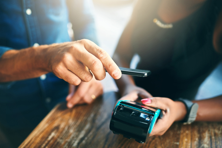 Person holding a cell phone over a contactless credit card reader