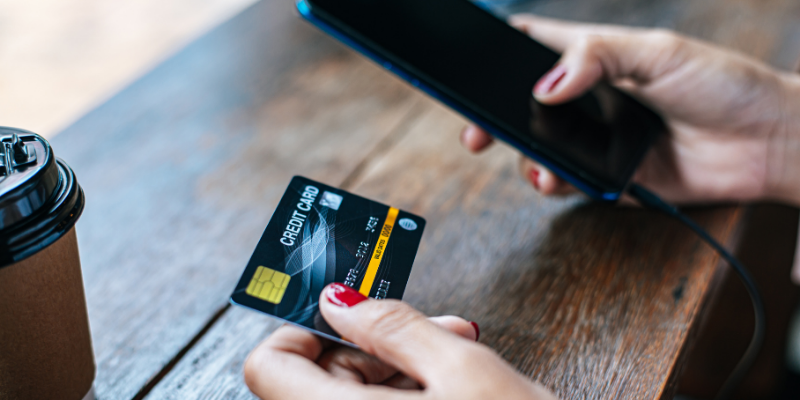 Person holding credit card in one hand and smartphone in the other hand