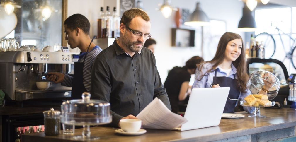 A person sitting in a cafe in front of a laptop.