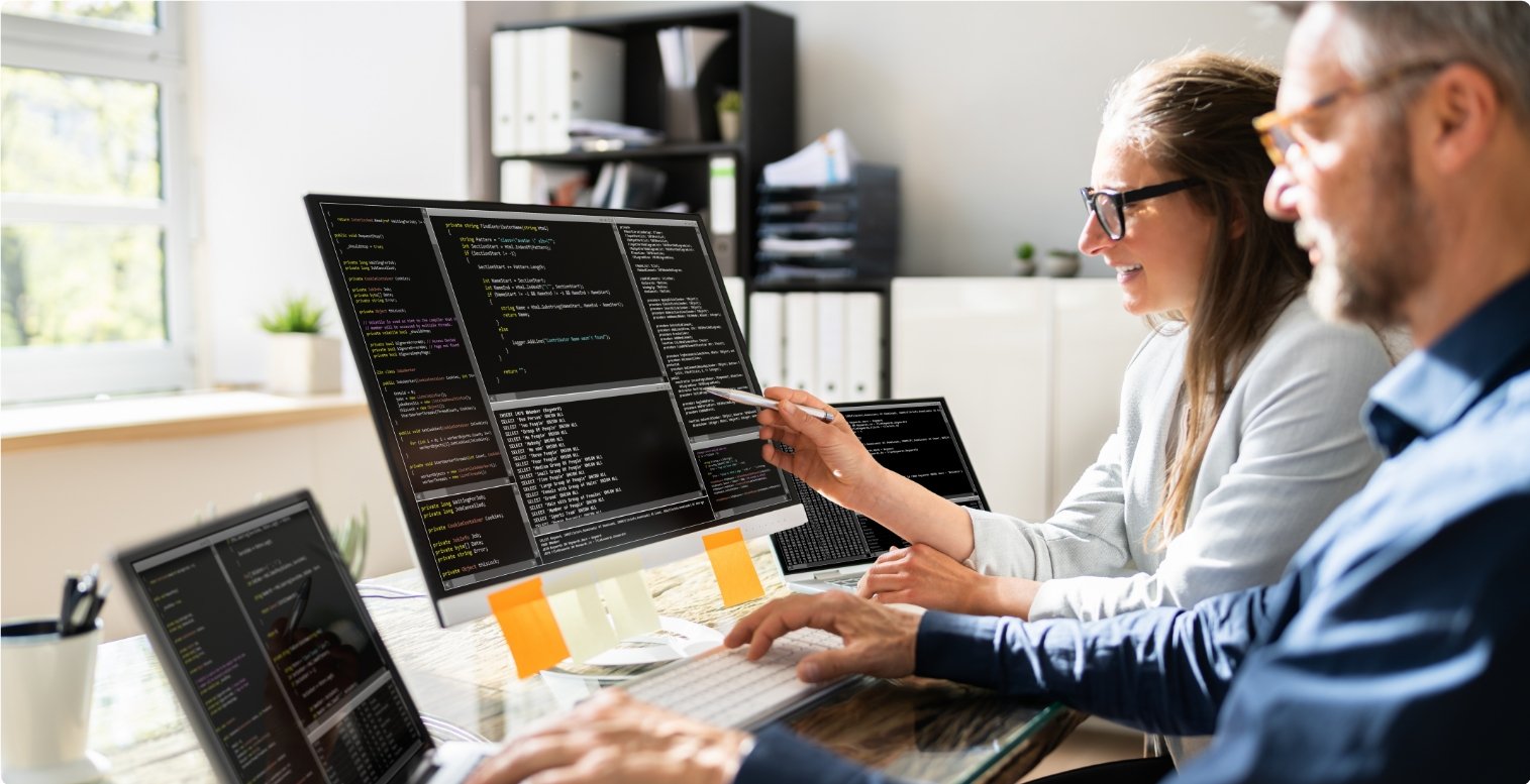 Woman wearing glasses points to her computer screen and explains how the PayFac model works to the man sitting next to her.