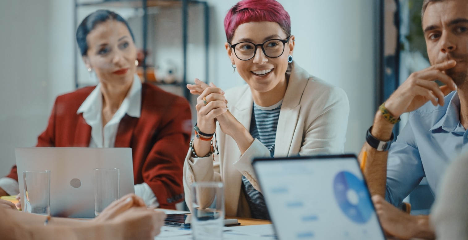 Three people sitting next to each other at a table watch someone give a presentation on payments trends