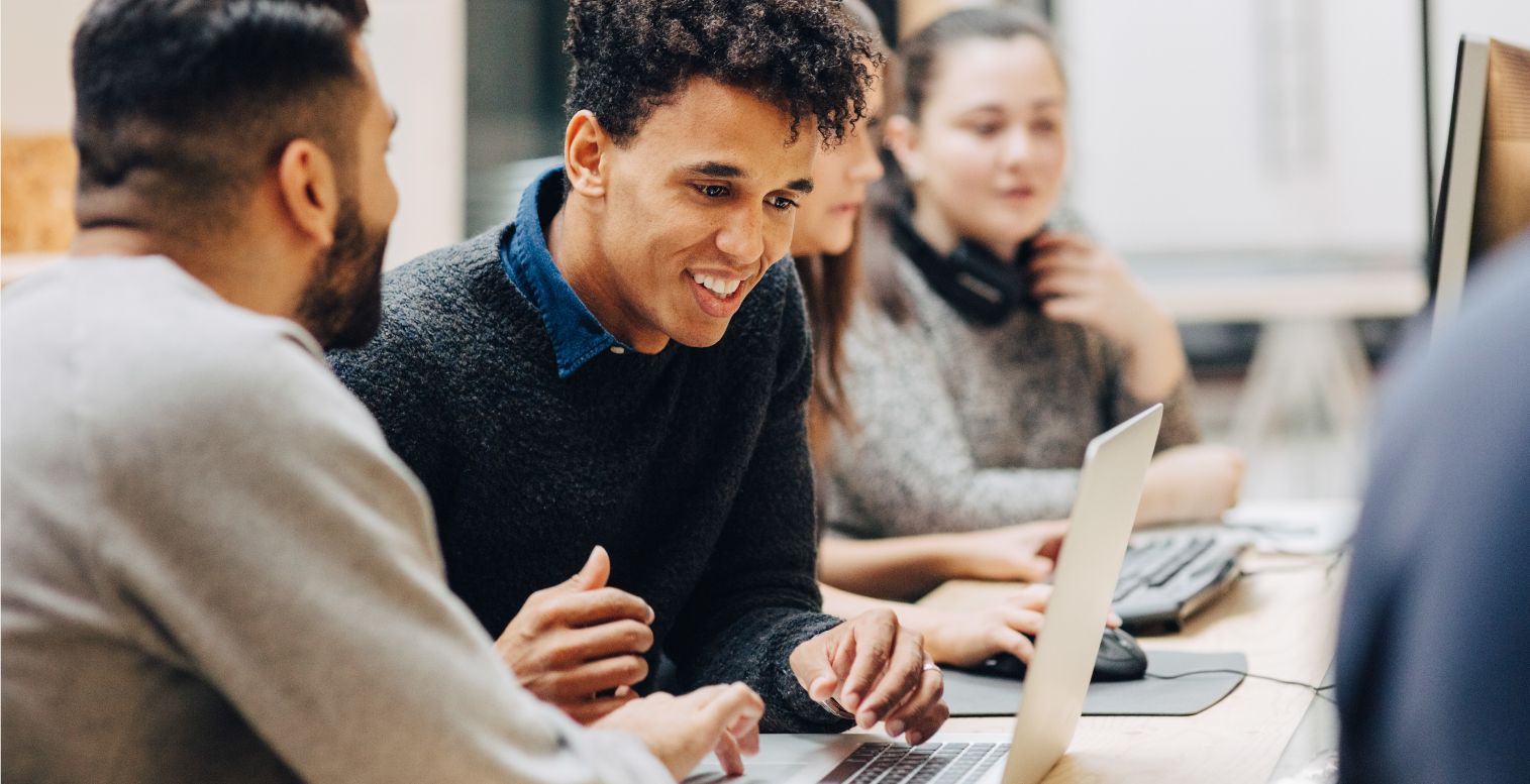 Two male employees smiling at an open laptop