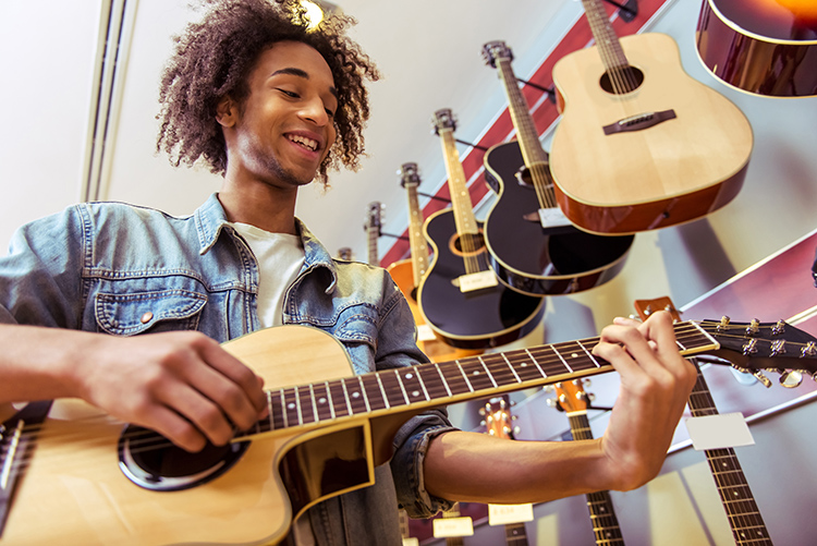 man playing guitar at a guitar retail location