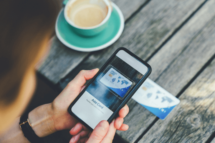 Man sitting at table using a mobile phone to take a picture of the credit card on the table