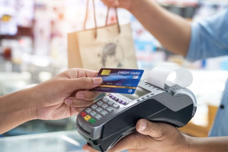 Shopper taps a contactless credit card to a card reader at a retail store