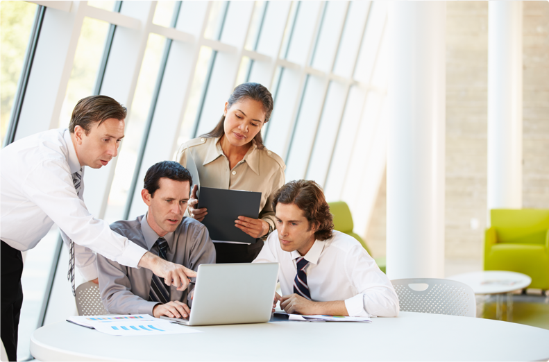 four professionals looking at a computer screen discussing PCI compliance
