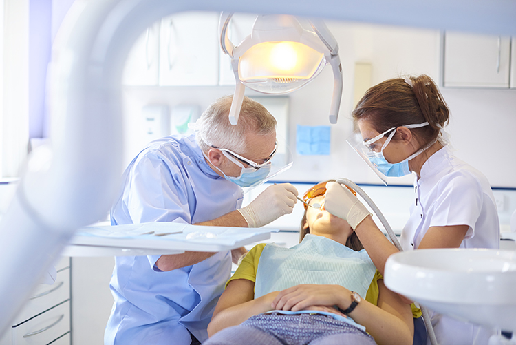 two dentists working on a patient in dental chair