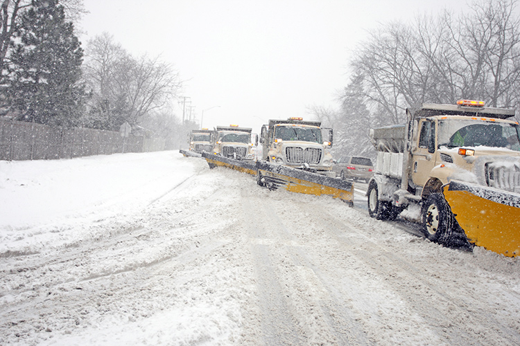 snow plows lined up removing snow from road