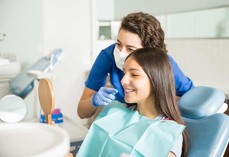 dentist showing a girl her smile in the mirror